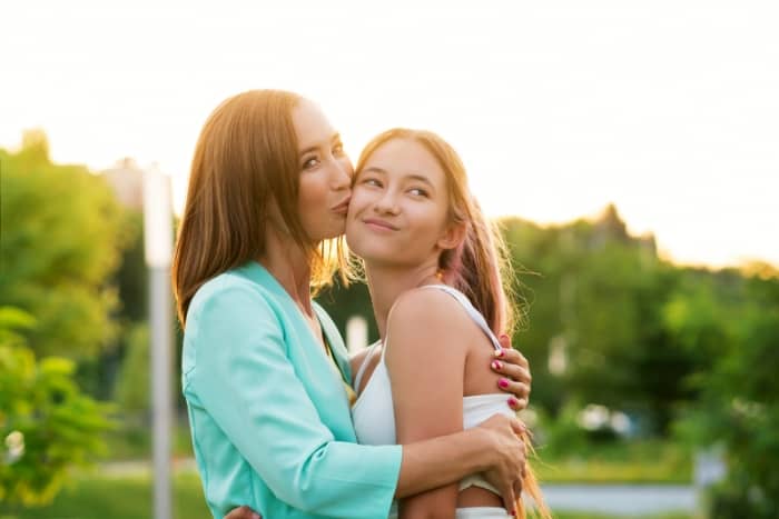 a mom is kissing her daughter